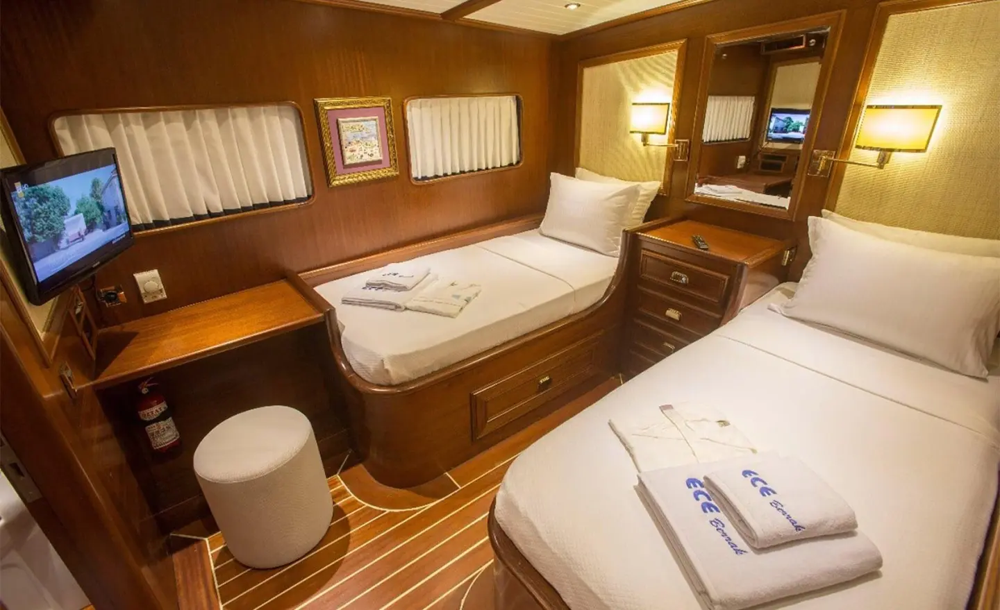 Elegant yacht cabin with two single beds, warm wood tones, porthole light