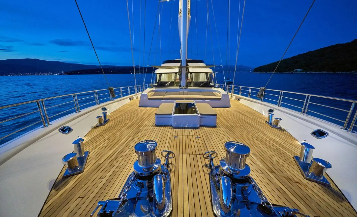 Bow deck view of Acapella yacht with seating, blue sky, and rails