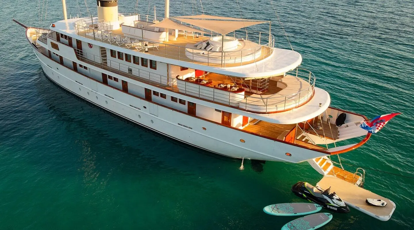 Bellezza luxury yacht anchored in clear teal waters with sunlit deck and open upper lounge