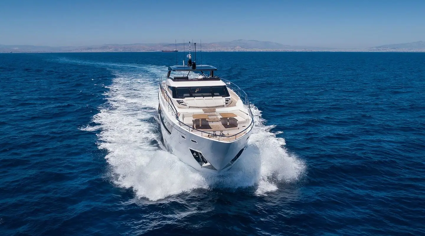 A white motor yacht named Spica cruises through blue sea, bow cutting waves