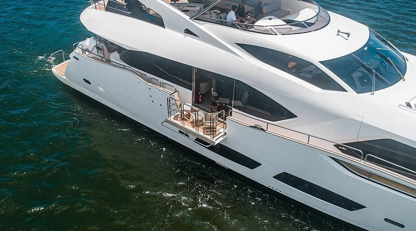 Quantum yacht anchored with passengers on deck near calm water, luxury vessel