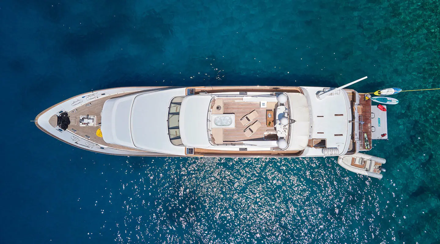 Top-view of Idylle yacht anchored in clear blue water, sunlit deck