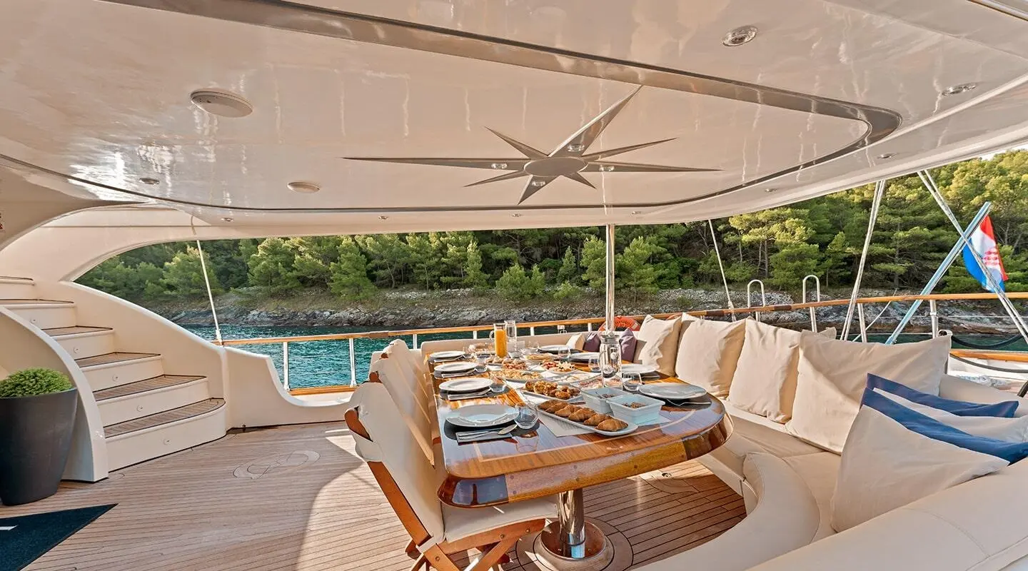 Gulet Alessandro I dining area aft deck with wooden seating and table setup