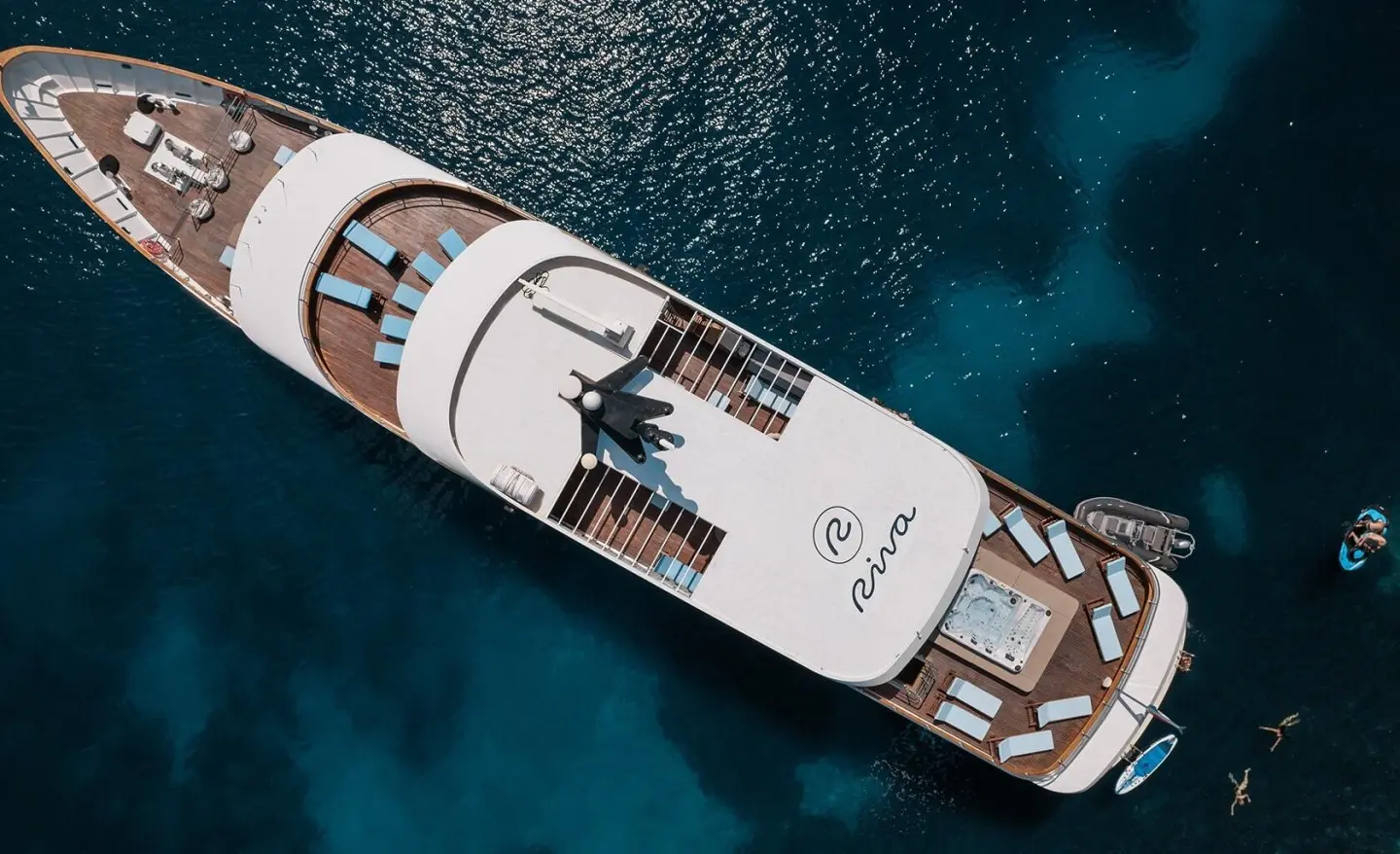 A sleek Riva luxury yacht anchored on calm blue water during sunset