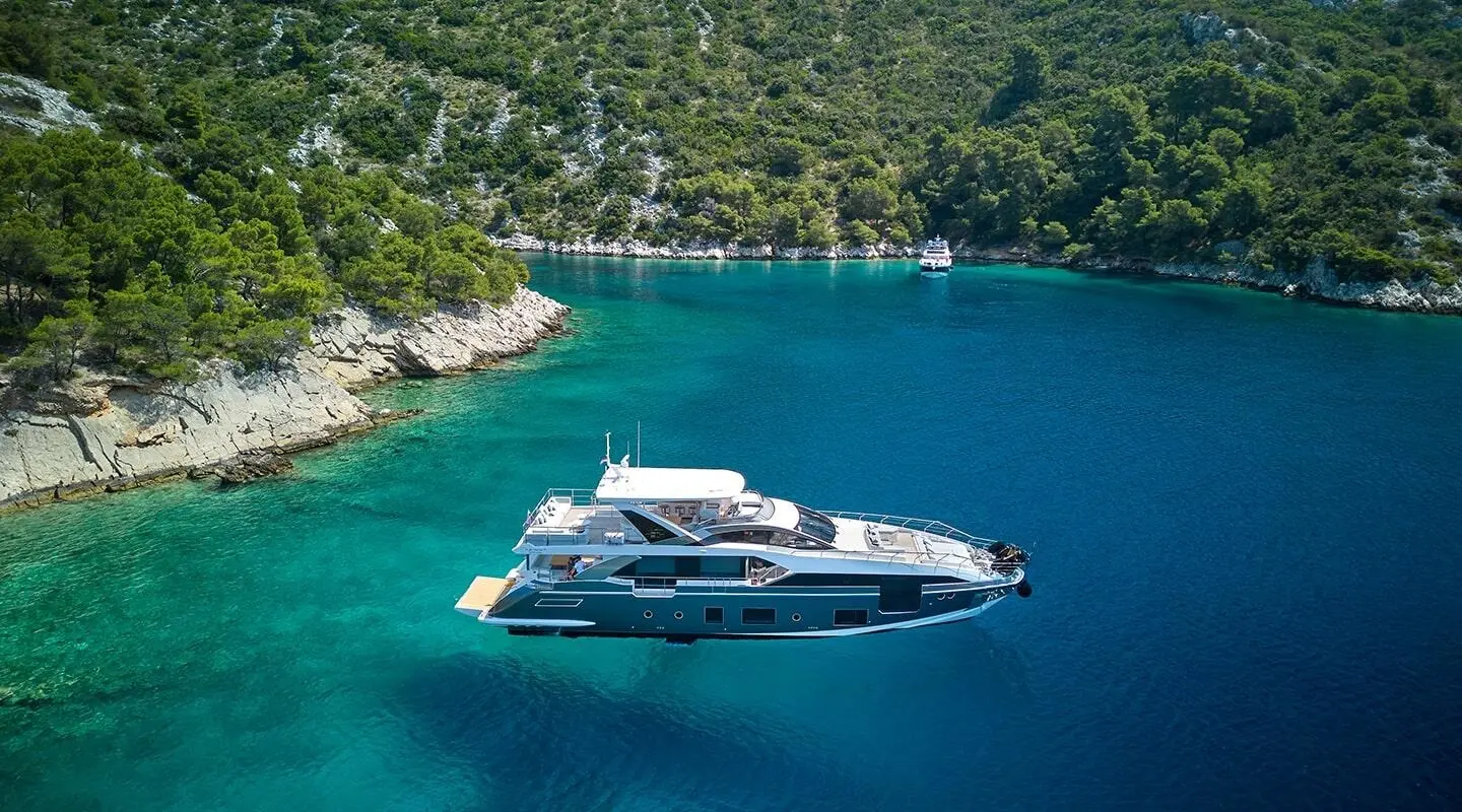 Aluminia Too yacht anchored near a rocky coastline with clear turquoise water