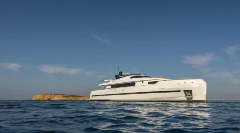Side view of Yacht Project Steel cruising on calm blue water under clear sky