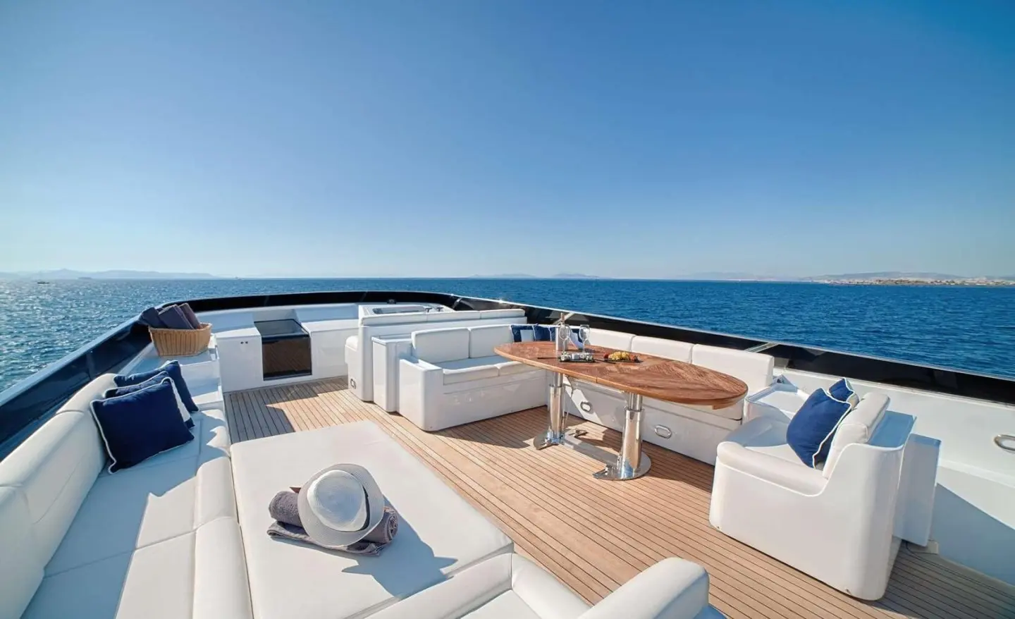 On the Zoi yacht's open deck seating area with a wooden table and white sofas, sea view