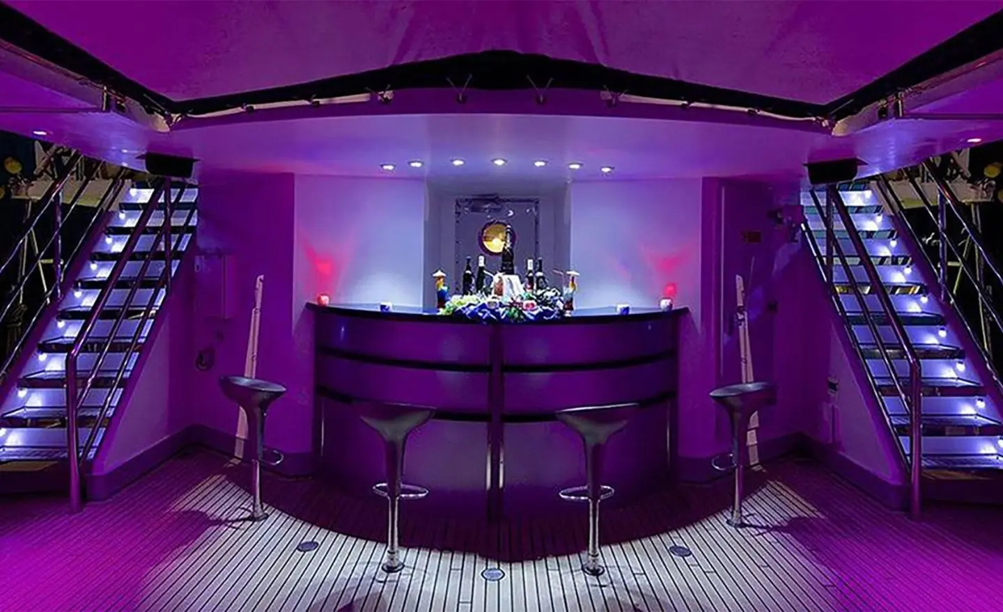 Inside view of a luxury yacht bar with purple lighting and seating