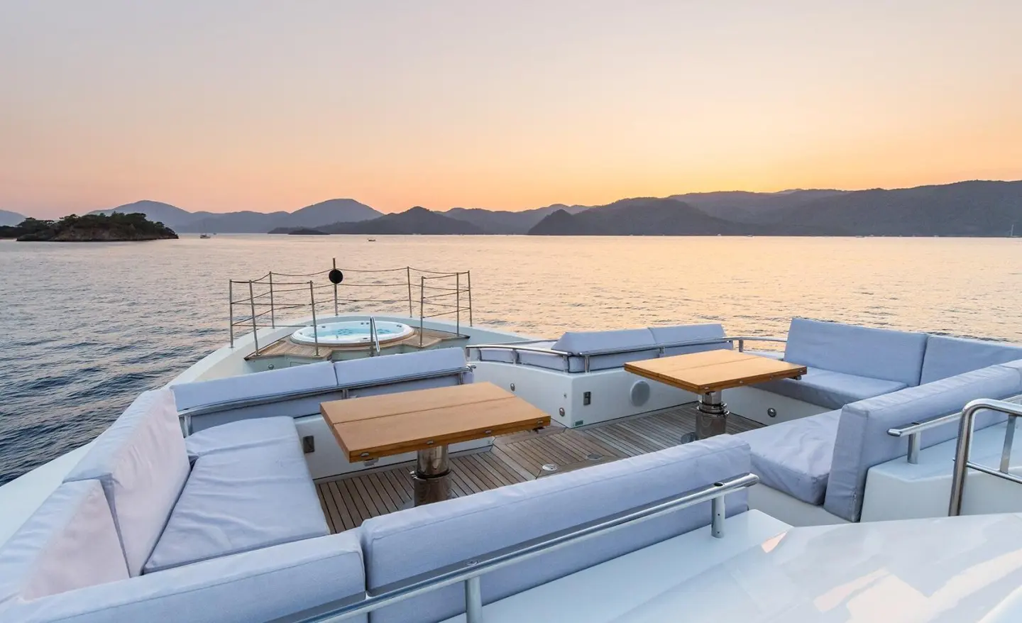Takara One yacht bow deck with sun beds overlooking calm sea at sunset
