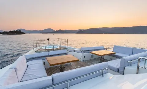 Takara One yacht bow deck with sun beds overlooking calm sea at sunset