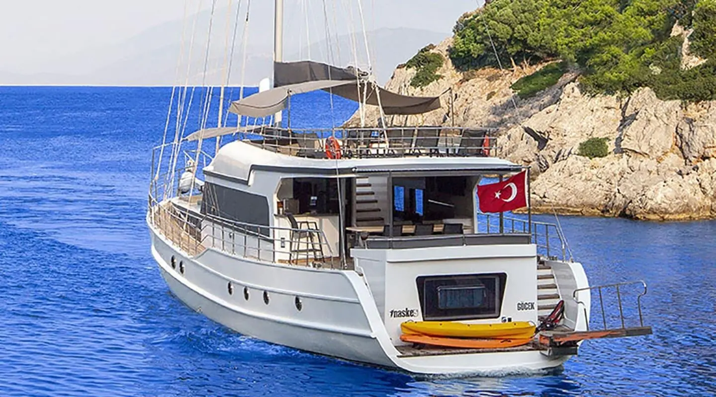 Yacht Maske 5 anchored at sunset with deck seating and blue awning visible