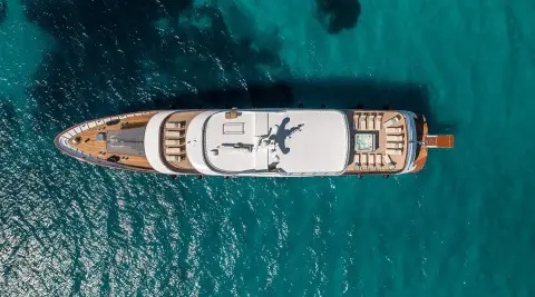 Overhead view of a white motor yacht named Olimp anchored in turquoise water