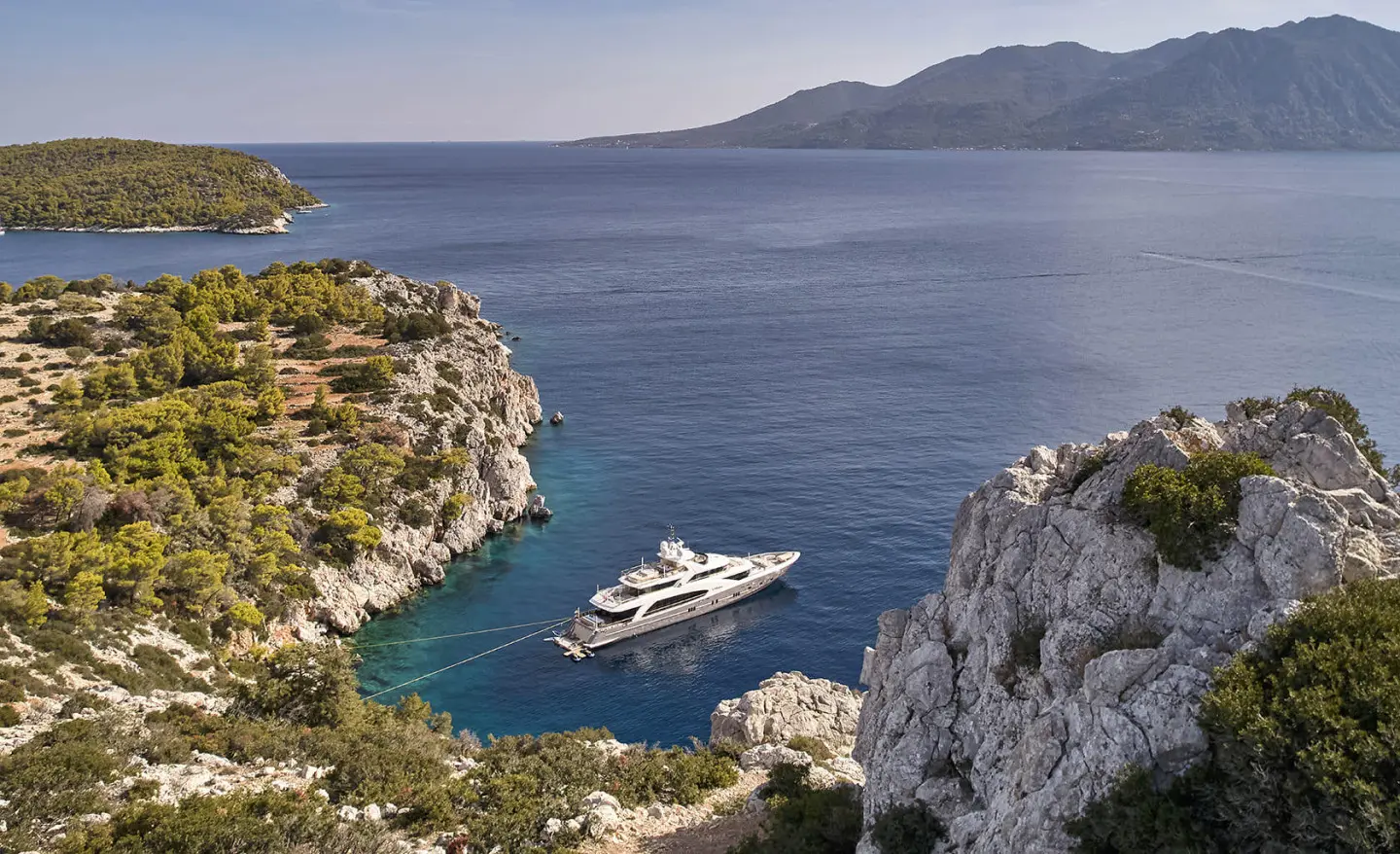 Yacht La Pellegrina 1 moored in a calm cove between rocky cliffs