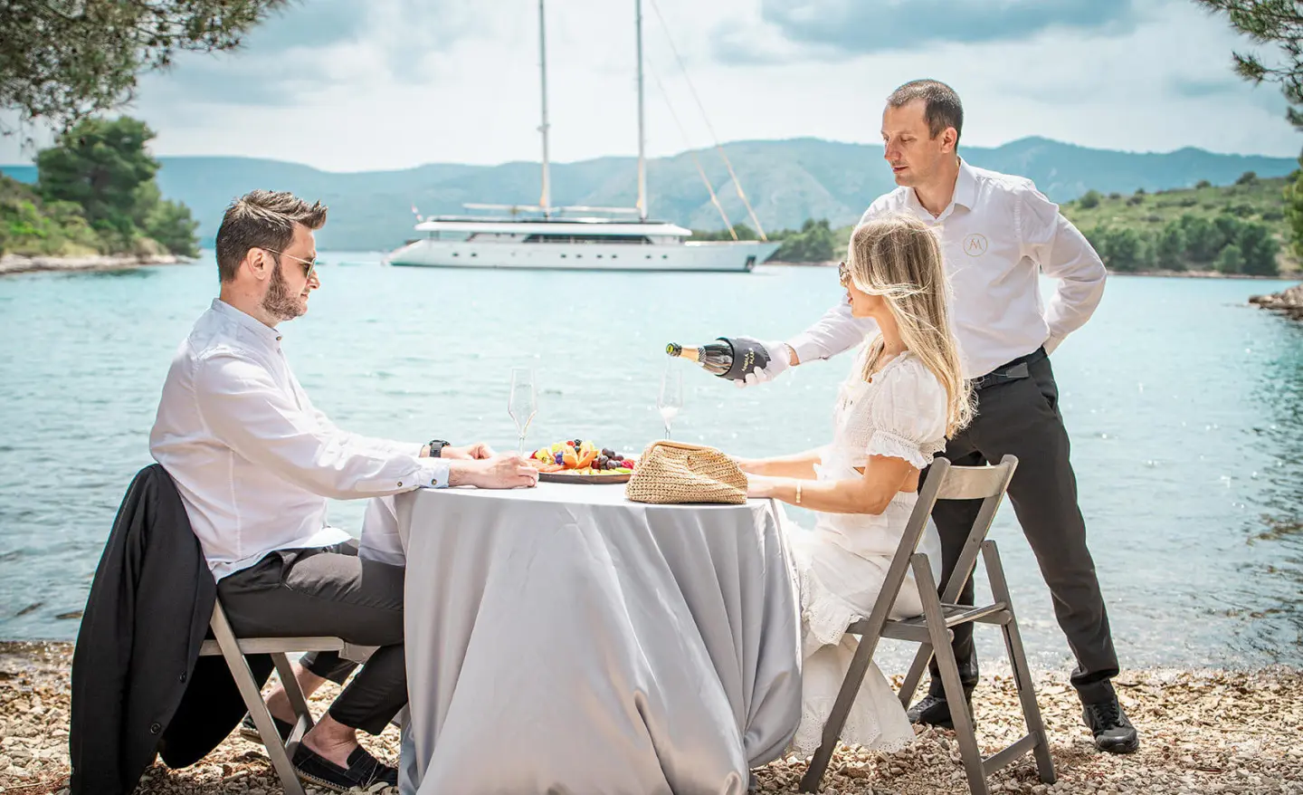 Anima Maris yacht charter table set for meal on deck by sea with guests
