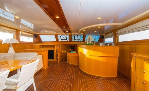 Wooden interior salon of a gulet-style yacht with cabinets and windows