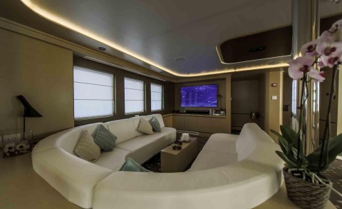 Interior of Omnia yacht: white sofas, central coffee table, TV unit and windows