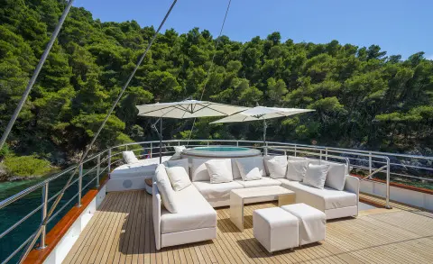 Maia motor yacht lounge area with white cushioned seating and large umbrella