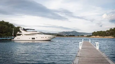 White large motor yacht docked at a marina with a pier in the foreground