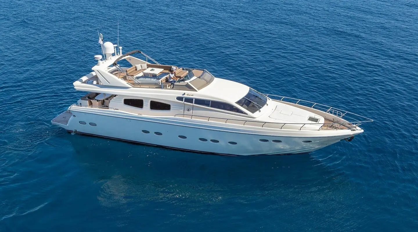 Amoraki yacht on open sea with upper deck seating and sunbathing cushions visible.