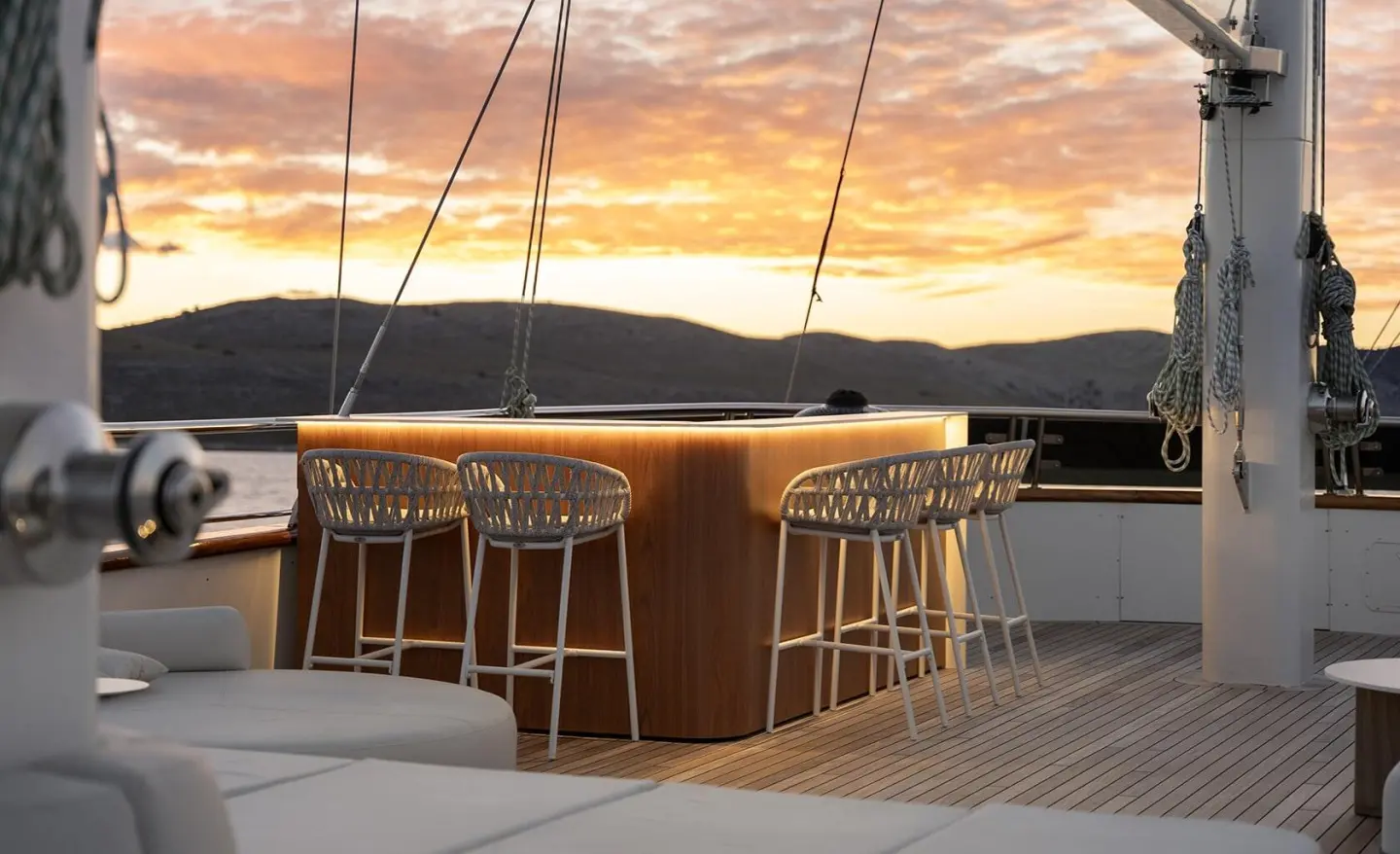 Maxita yacht deck at sunset with bar stools and railing, calm water