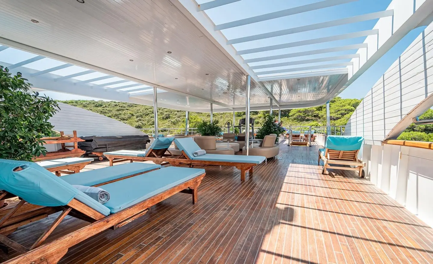 Sunlit yacht sundeck with blue cushions, wooden floor, and shaded seating area