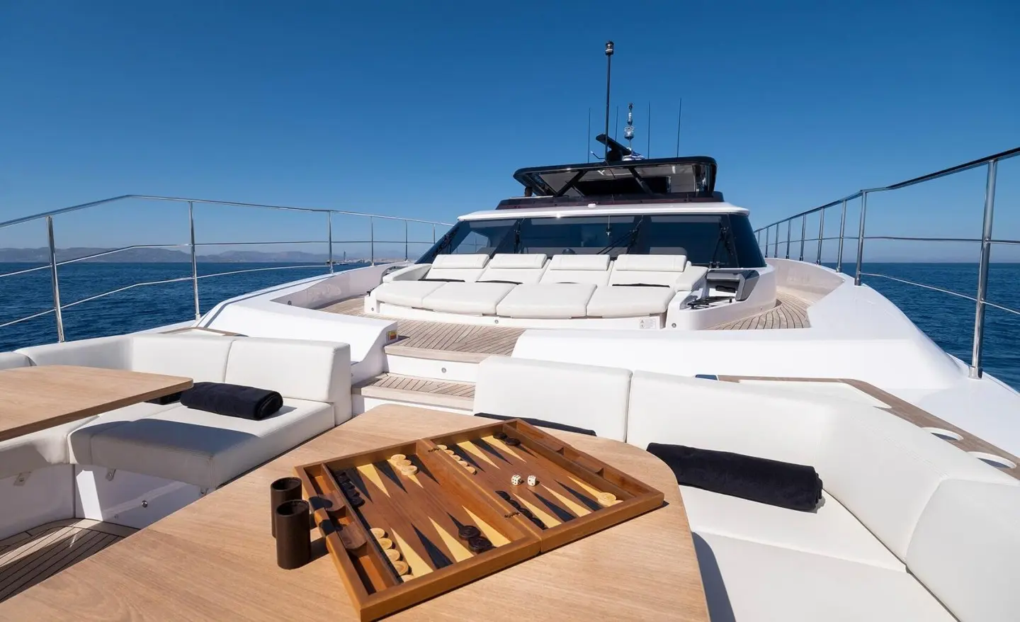 Spica yacht deck with white hulls, blue sea, and clear sky in view