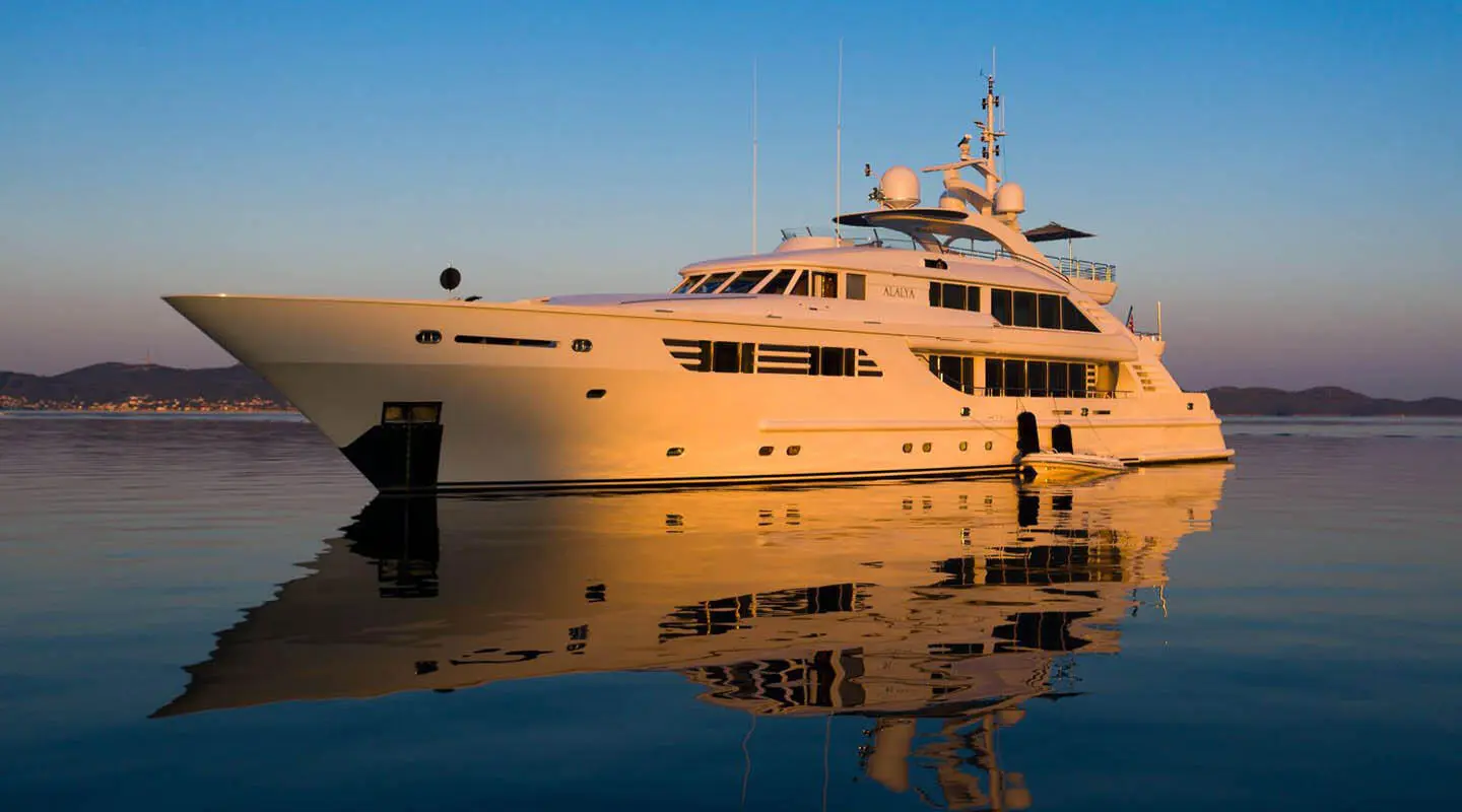 Alalya luxury yacht anchored on calm blue water at sunset, reflecting silhouette