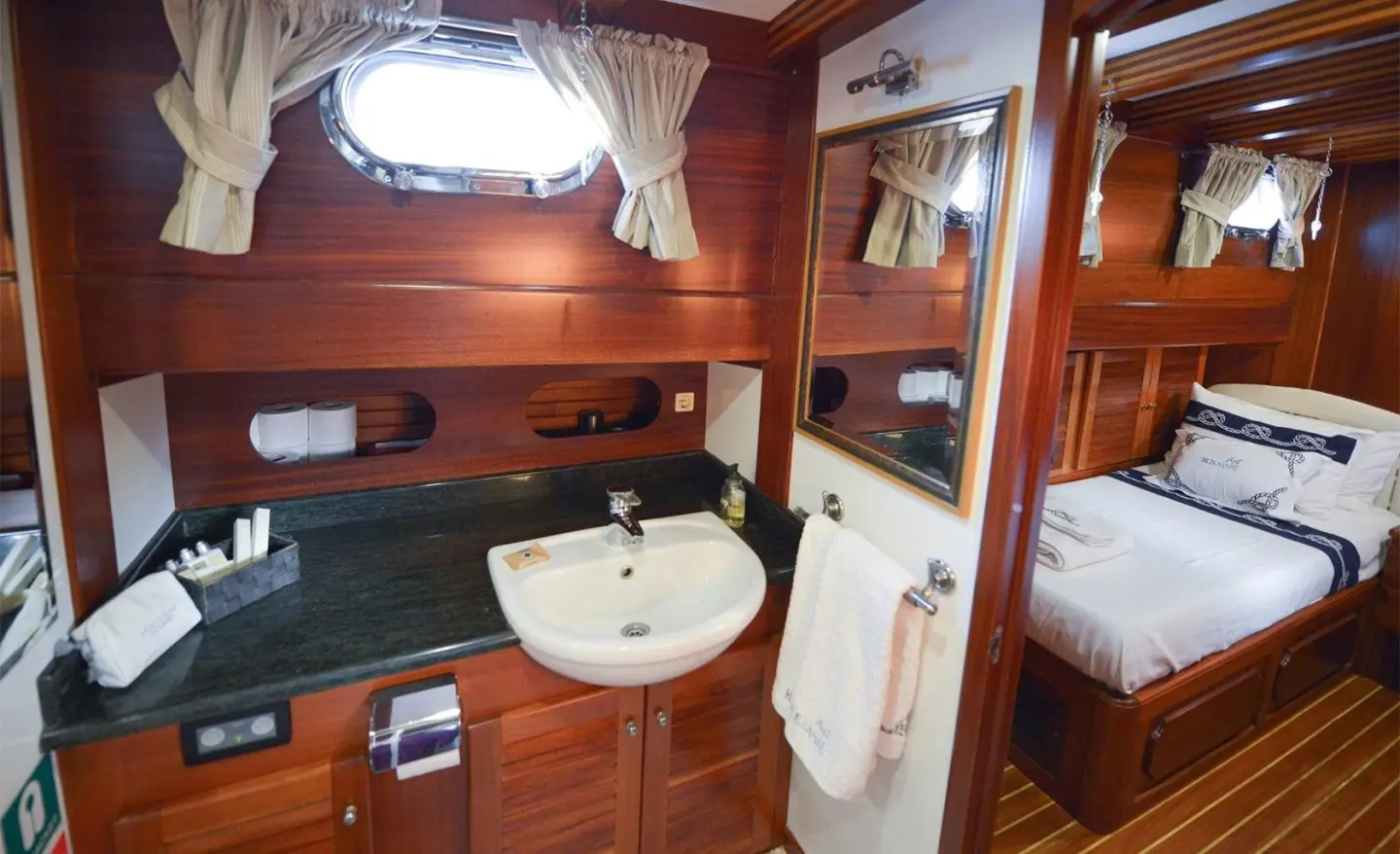 Inside a luxury yacht cabin with wooden panels, sink, mirror, and bed
