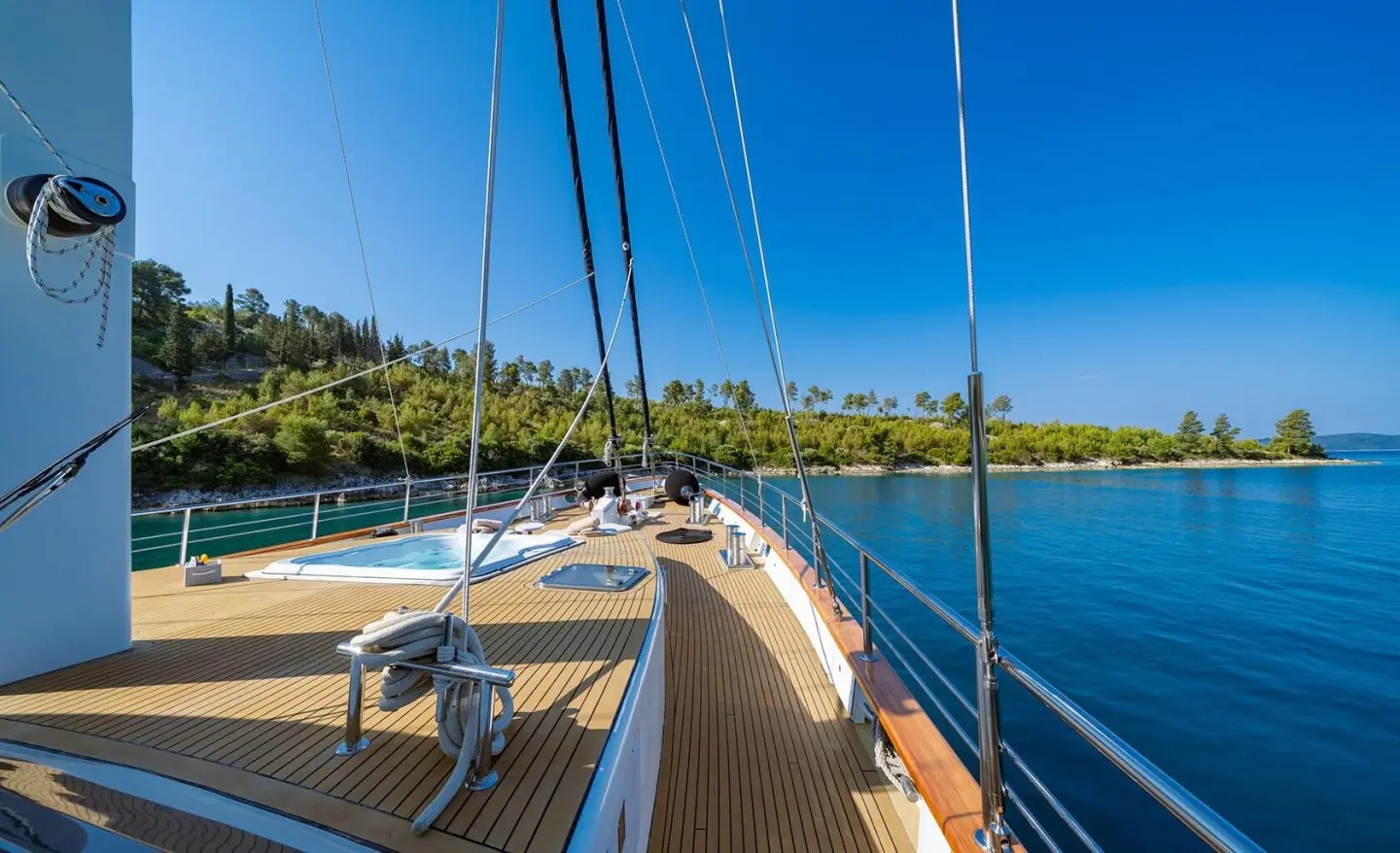 Navilux yacht deck at sunset, ropes and railing leading to calm blue sea