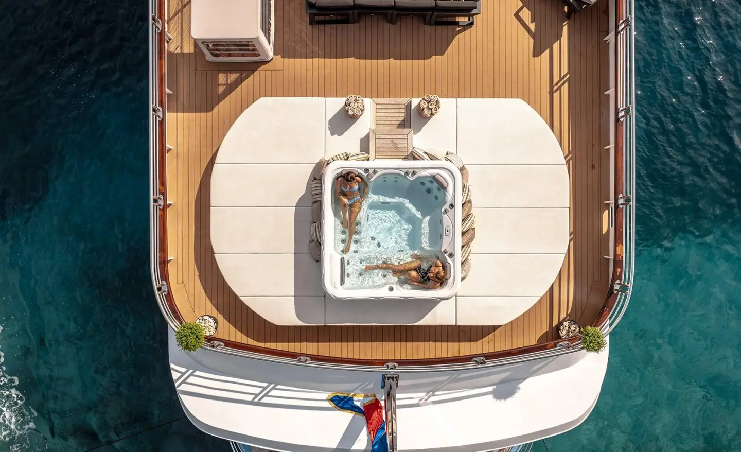 Top-down view of a luxury yacht deck with a circular hot tub and seating