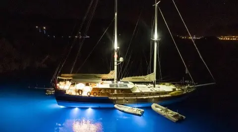Derin Deniz yacht at night, illuminated by lights, moored beside a dark sea