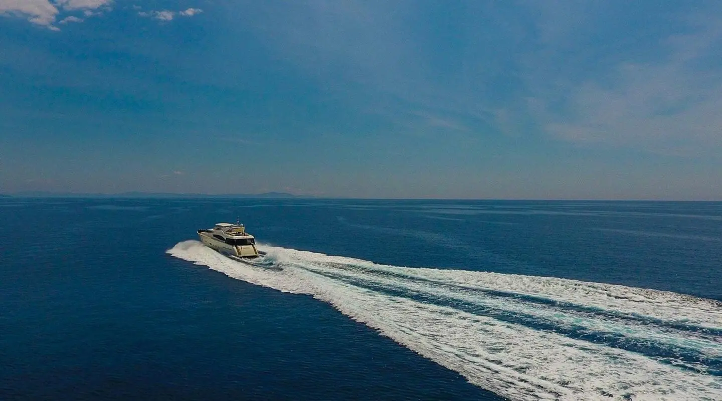White motor yacht cruising at speed on open blue sea
