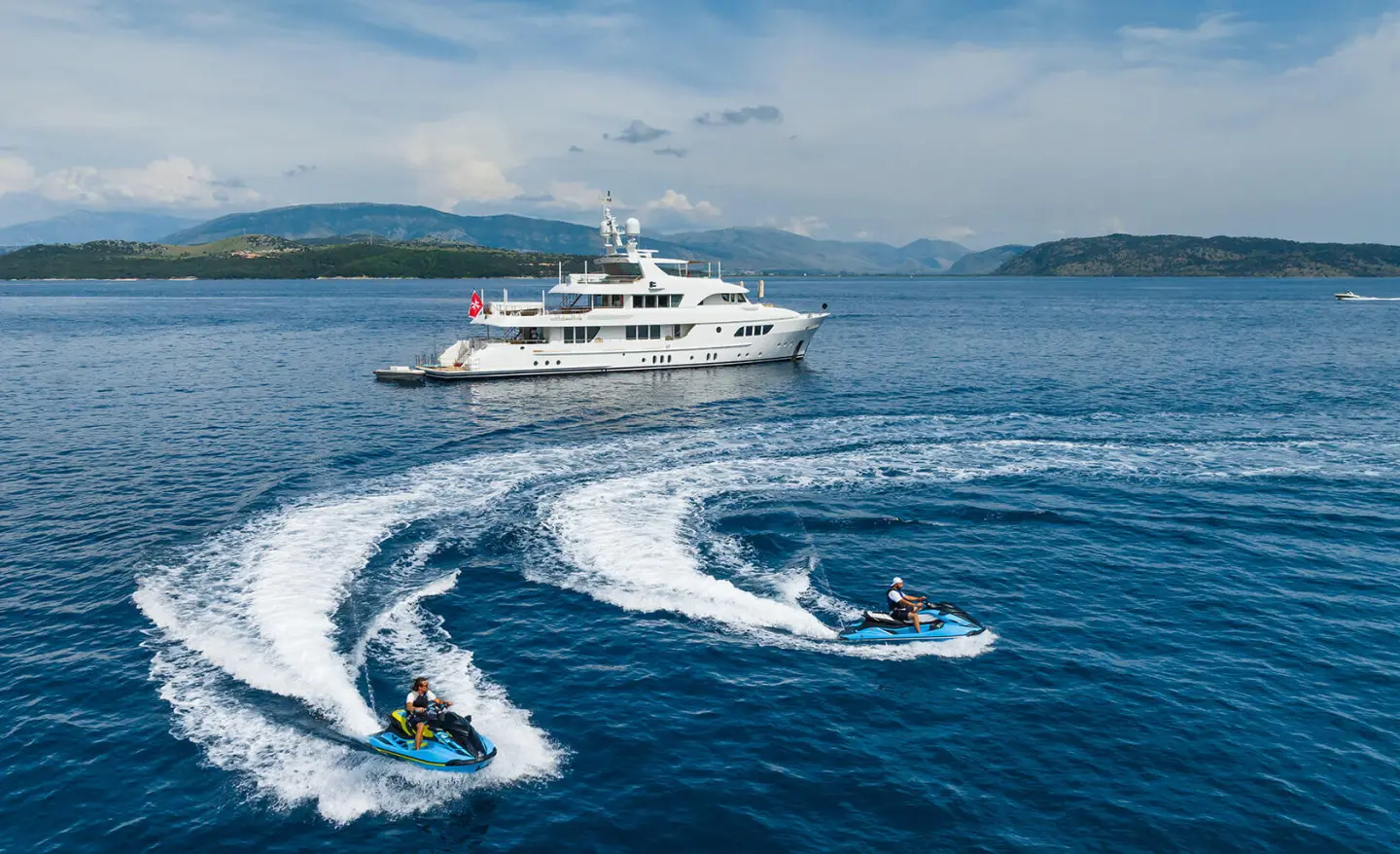Serenity yacht at sea with water sports boats speeding nearby and wake