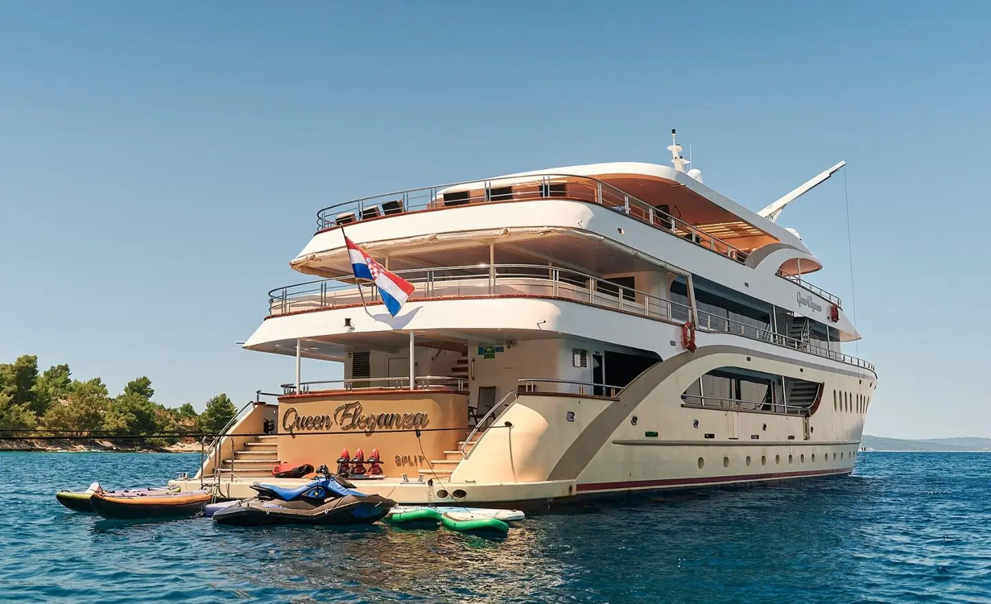Queen Eleganza yacht anchored with upper decks and water toys visible