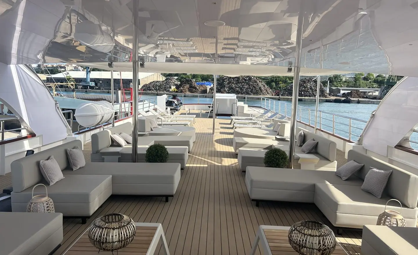 Salon on Melody yacht with white cushioned seating and teak deck under a covered area
