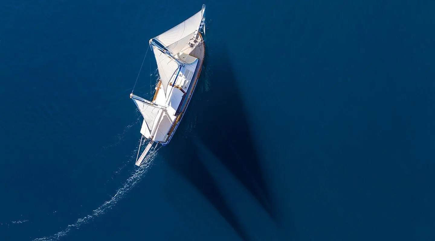 Andi Star yacht anchored at sunset with white sails and calm blue water