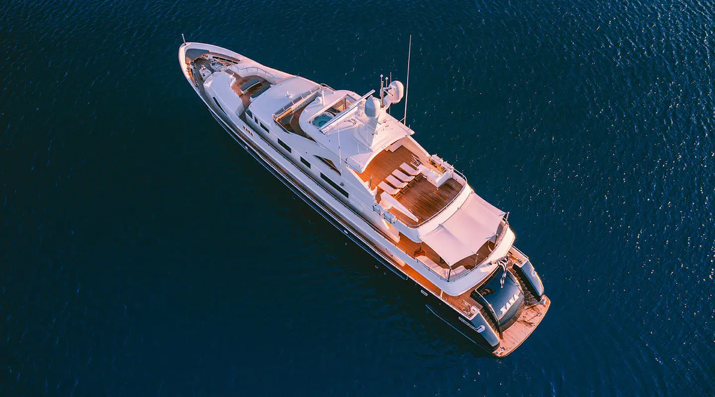 Top-down view of Xana yacht anchored in dark blue water, white hull and deck