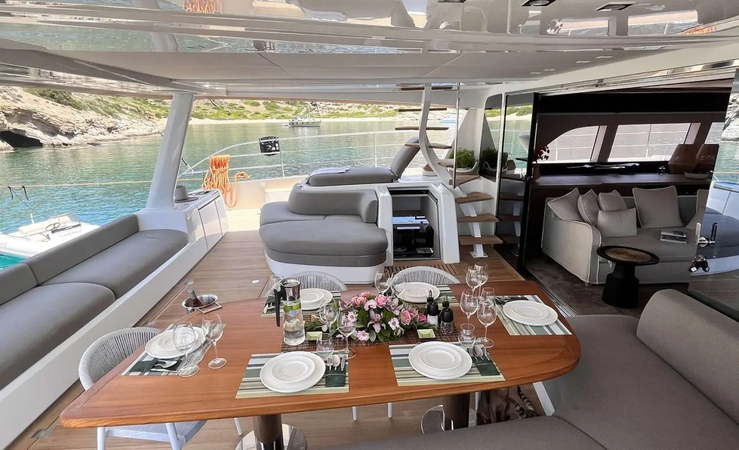 Outdoor deck with dining table and seating, sea and rocky shore in background