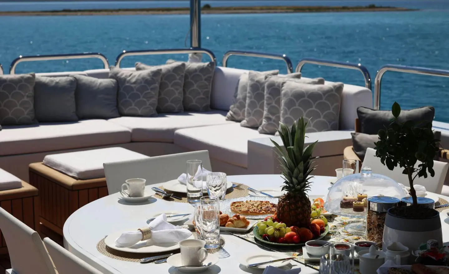 Alalya luxury dining on yacht deck with white tables and ocean view