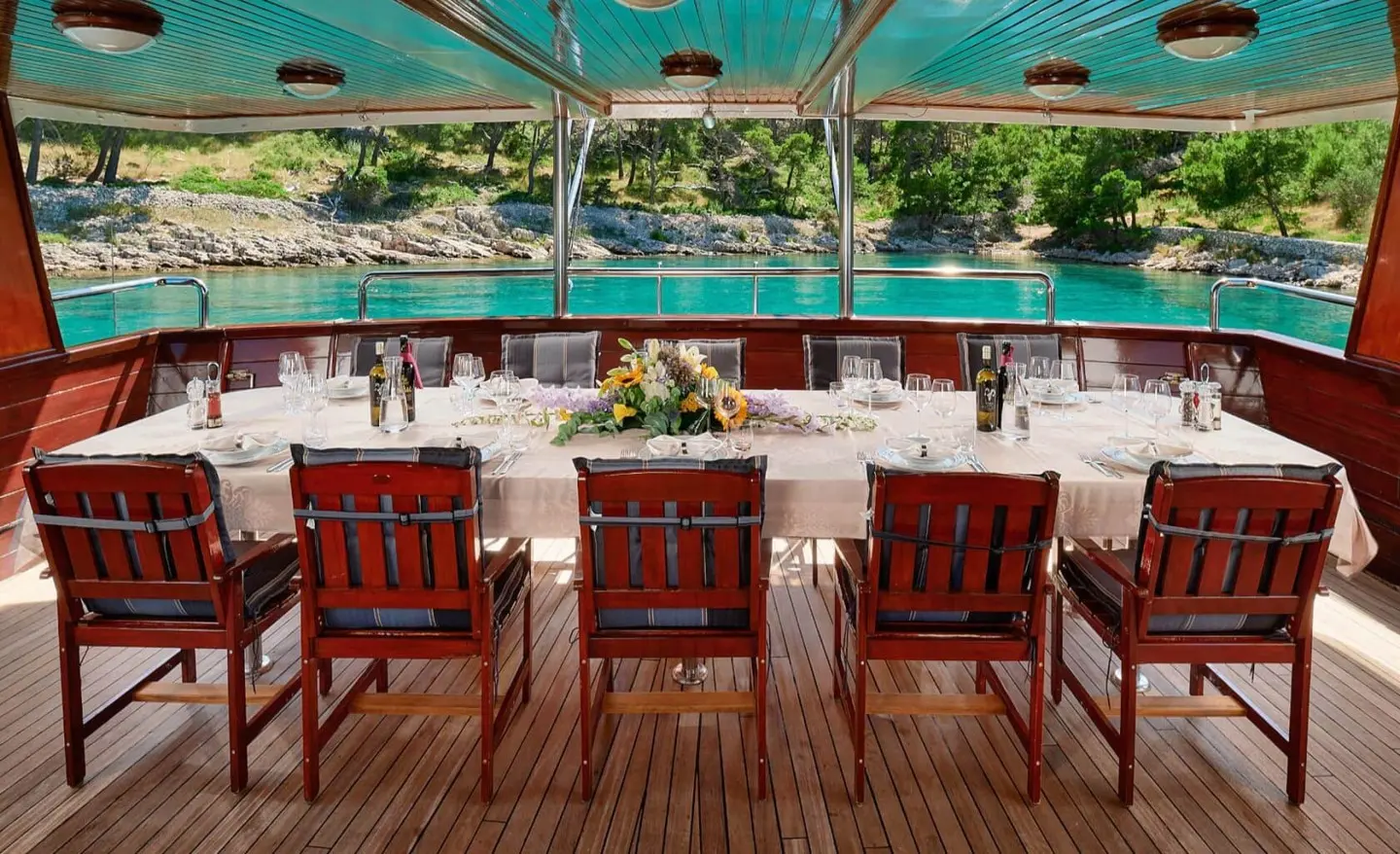Luna yacht outdoor deck with four red wooden chairs facing turquoise water