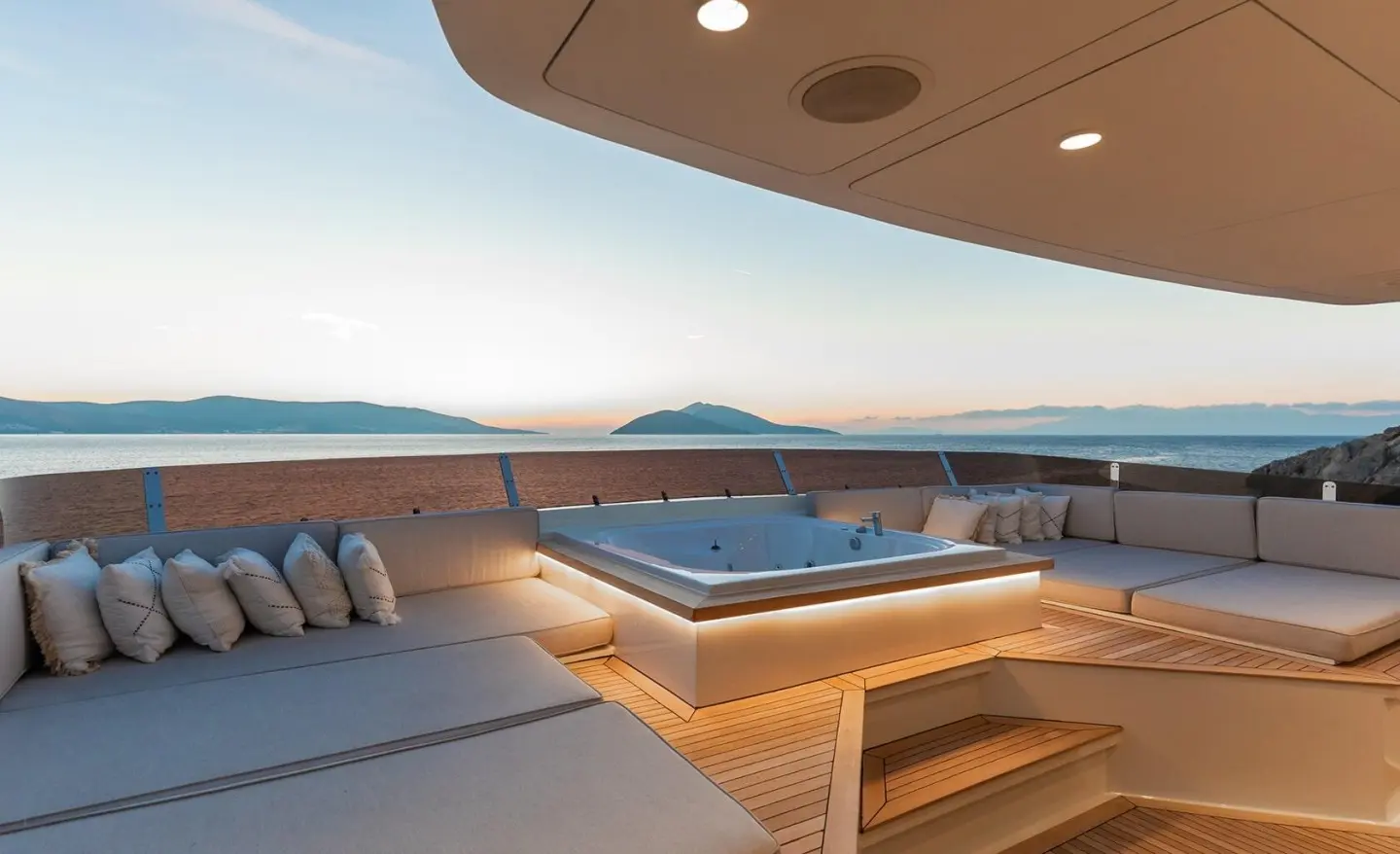 Outdoor yacht deck with jacuzzi and lounge seating, sea and distant islands