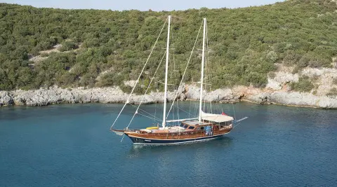 Samarkand yacht sailing near rocky coastline at sunset with masts and sails
