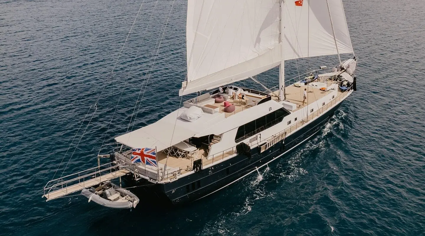 Yacht Good Life anchored at sea with sails raised at sunset