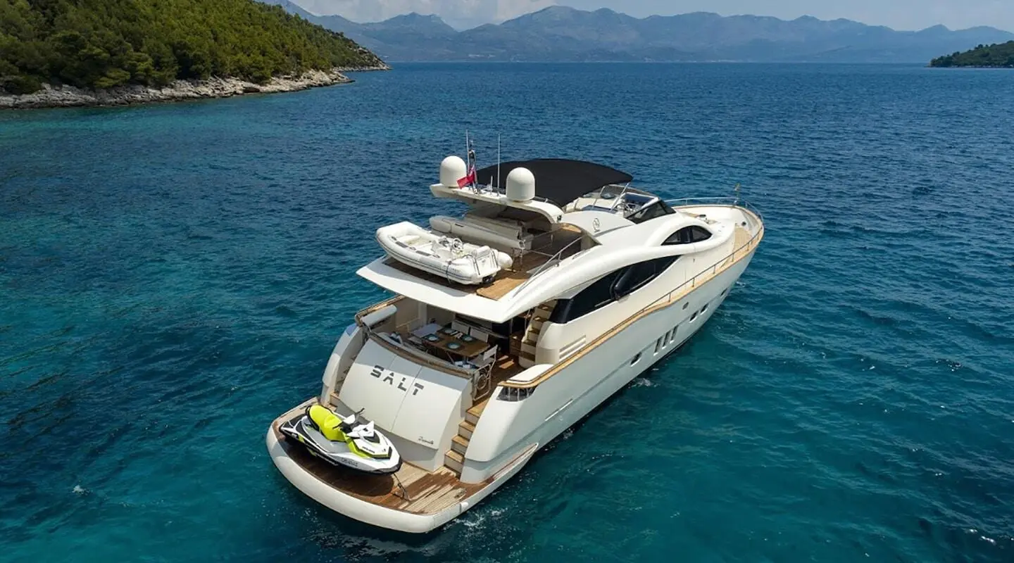 Salt yacht shown with its upper deck and stern, anchored on clear blue sea