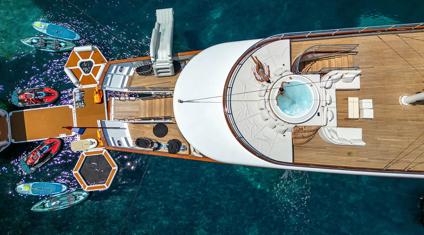 Aerial view of Maia yacht deck with white canopy, teak flooring, and blue sea surrounding