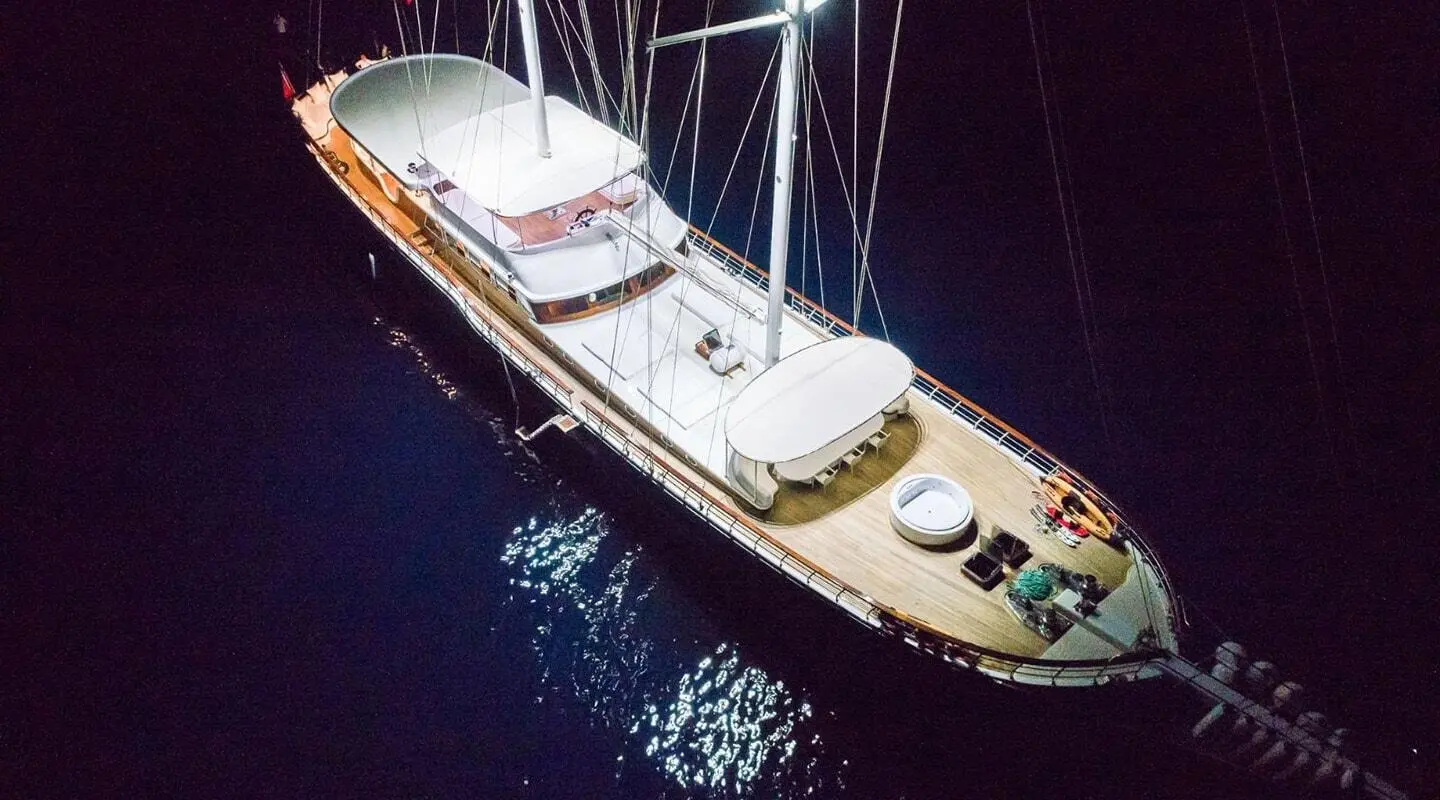 Gulet Halcon Del Mar at night, moored alongside with lights reflecting on calm water