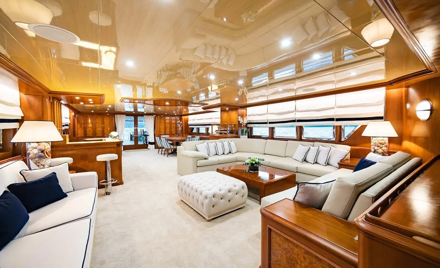 Cozy yacht saloon with plush beige seating, wooden trim, and large windows