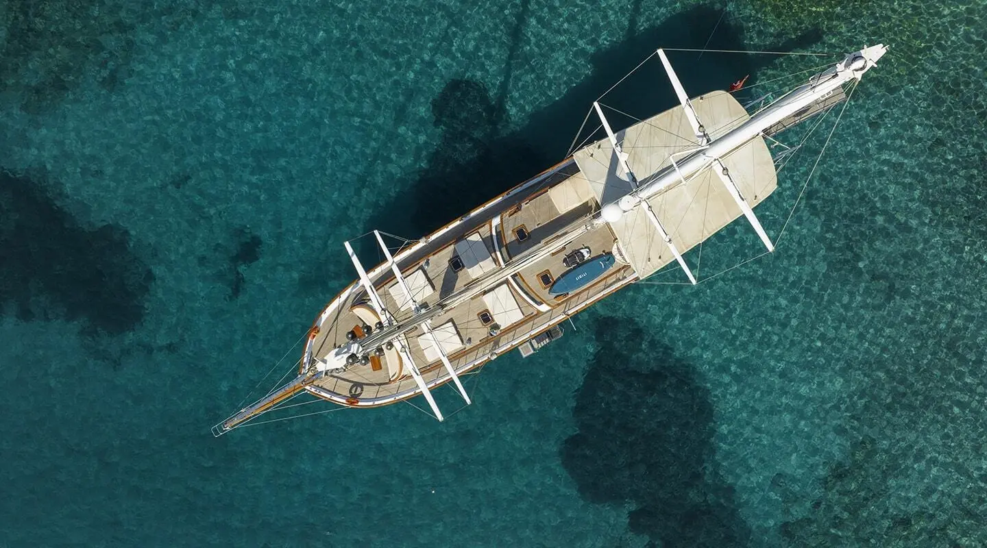 Aerial view of Artemis luxury yacht anchored in clear tropical blue water at sunset