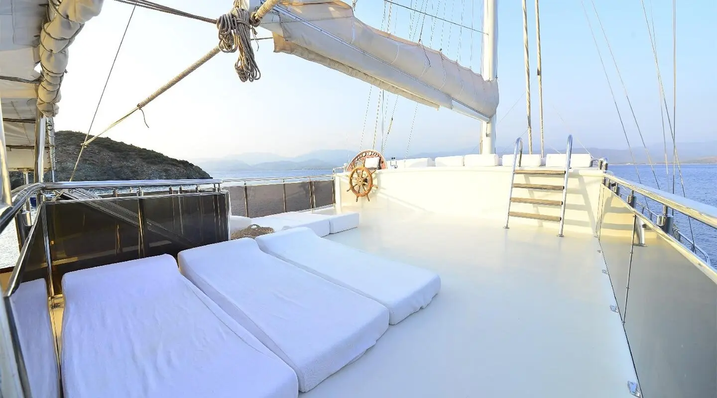 Sunlit yacht deck with white cushions and blue ocean horizon at sunset