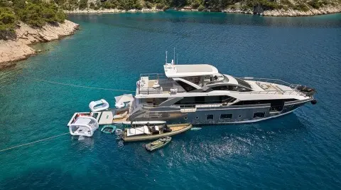 Aluminia Too yacht anchored near calm blue water at sunset with small boats nearby